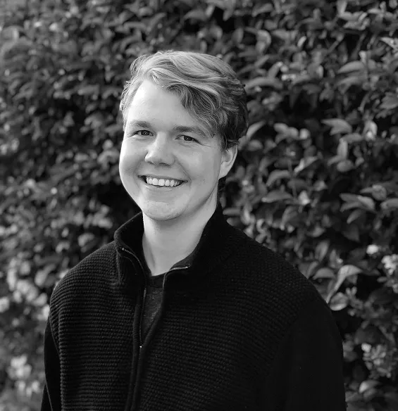 Caleb Raney, smiling, in front of a hedge.
